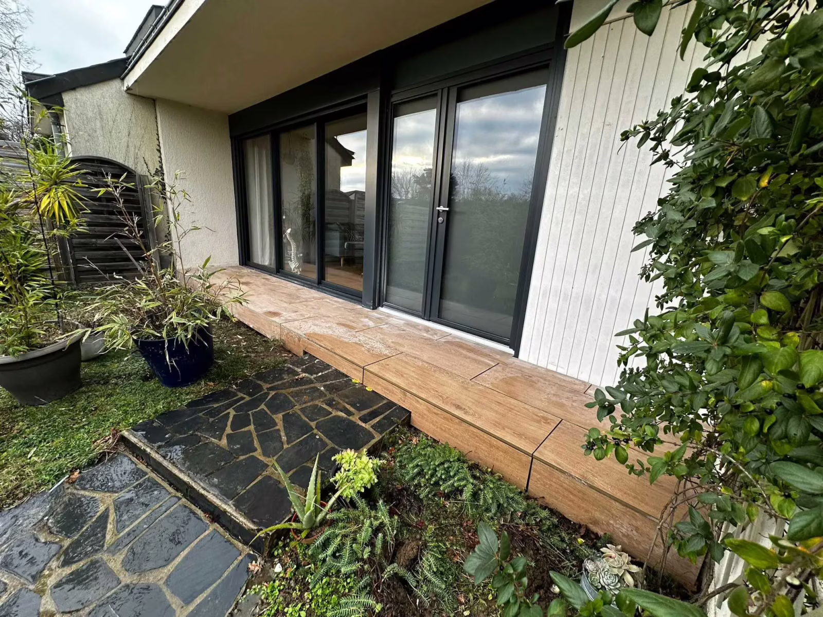 Terrasse bois et pas en ardoise devant une baie vitrée
