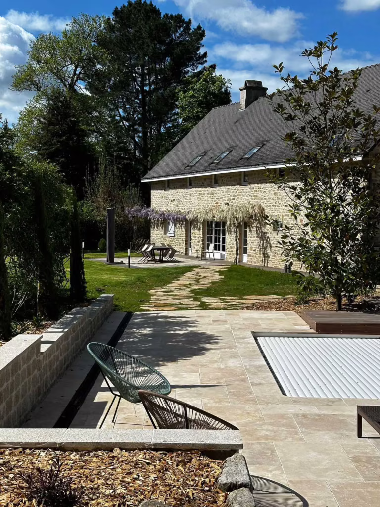 Terrasse en pierre et piscine devant une longère